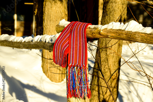 ceinture fléchée (traditional pattern) replica of the woven sash worn by voyageurs during the fur trade shot on a wooden fence rail with snow  room for text photo