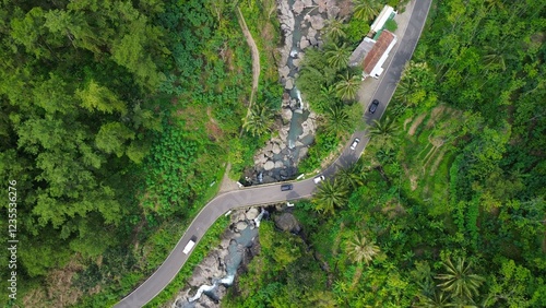 Road by a flowing river, in the middle of forests and hills with lush trees in Sempor Kebumen Central Java photo