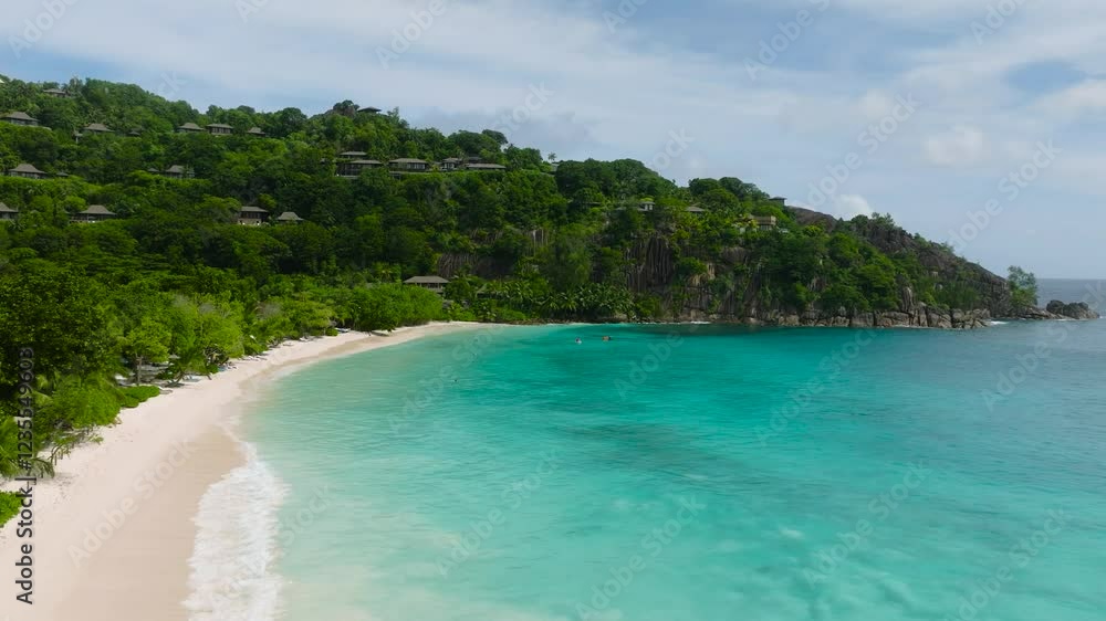 Panoramic view showcasing a turquoise bay surrounded by green hills and lush vegetation. Petite Anse. Seychelles, Mahe. Panoramic view showcasing a turquoise bay surrounded by green hills and lush vegetation. Petite Anse. Seychelles, Mahe.