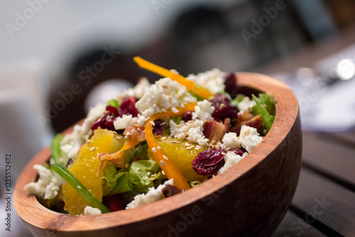 Fitness salad with ricotta cheese and dried cranberries on a rustic wooden bowl, side vew close-up. photo