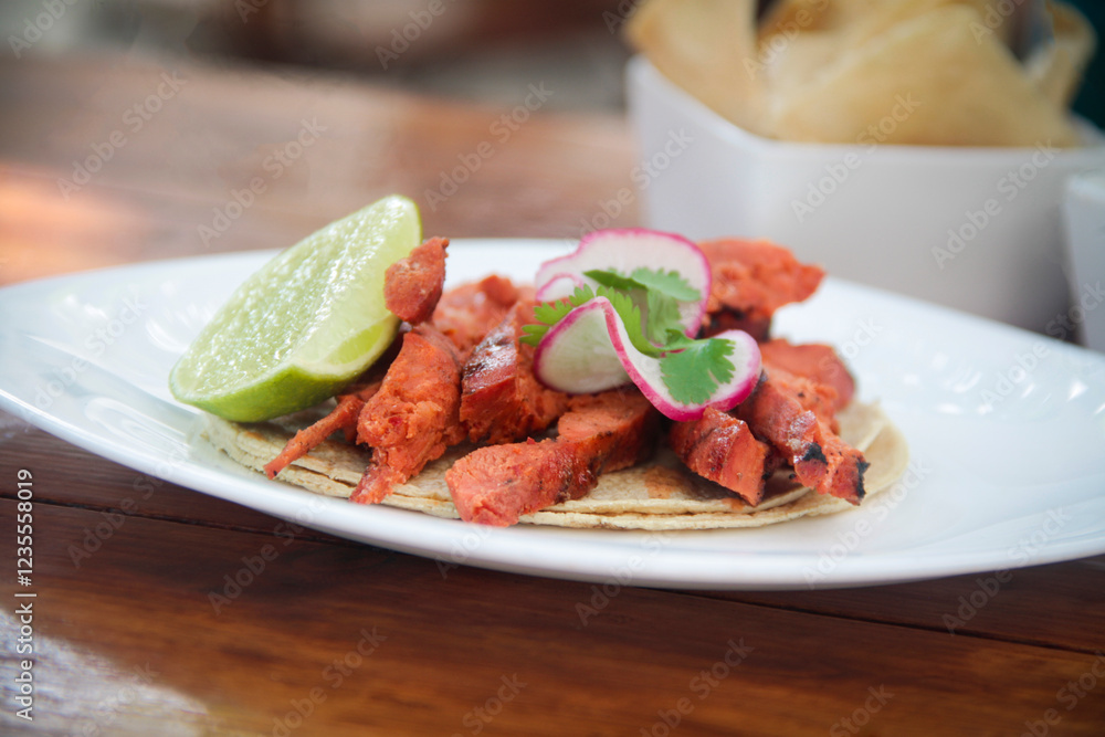High-angle view of a grilled chorizo taco on a corn tortilla, garnished with radish slices, fresh cilantro, and lime, served on a ceramic plate. High-angle view of a grilled chorizo taco on a corn tortilla, garnished with radish slices, fresh cilantro, and lime, served on a ceramic plate.
