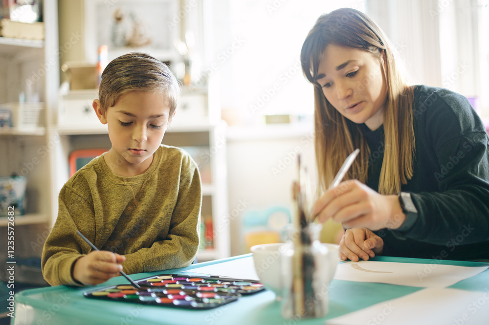 Fototapeta premium Painting, learning and art with teacher and child in classroom for creative, education and youth. Teaching, hobby and drawing with woman and young boy for picture, inspiration and artwork lesson