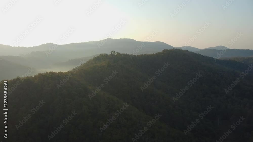 Beautiful sunset in the winter mountains. The setting sun shines down on a serene mountain landscape covered with tropical trees in the evening. Beautiful sunset in the winter mountains. The setting sun shines down on a serene mountain landscape covered with tropical trees in the evening.