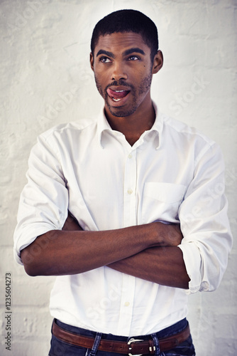 Fotografia Comic, playful and black man with arms crossed, funny face and isolated on white brick wall background