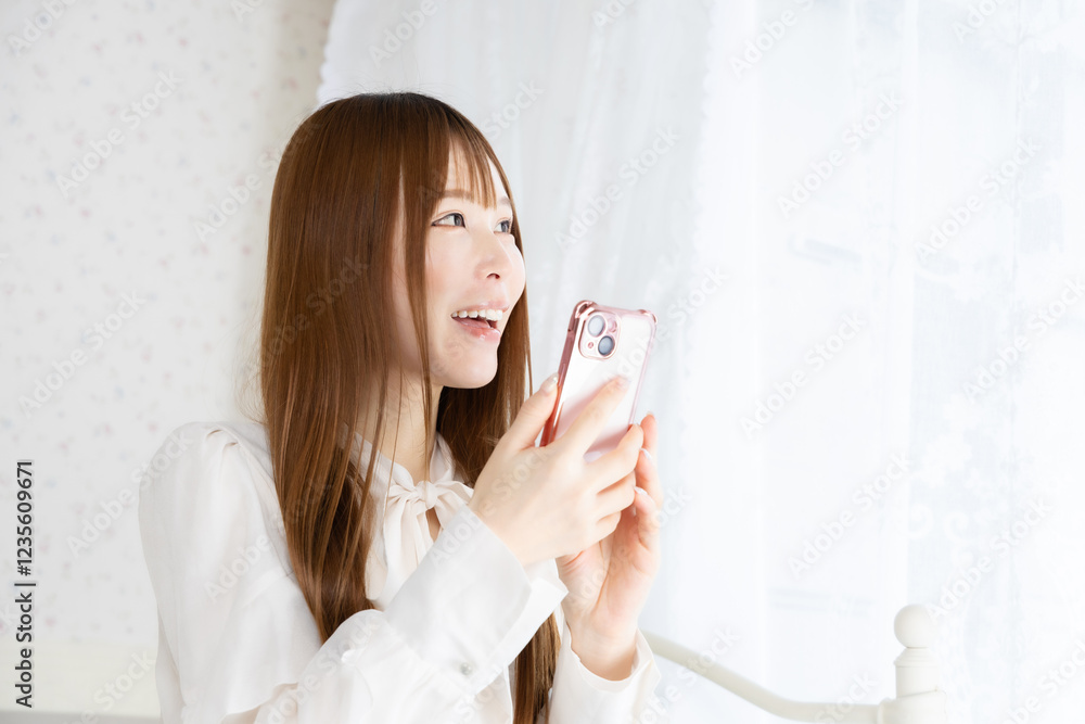 部屋でスマートフォンを持っている若い女性