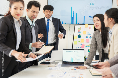 Wallpaper Mural Asian business group meeting to give advice on graphing and document work in the office Torontodigital.ca