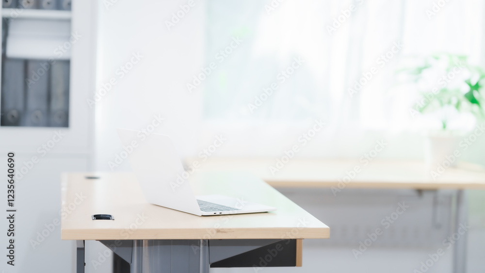 Fototapeta premium Blank white laptop on blank office desk with blurry white background for display your ads.