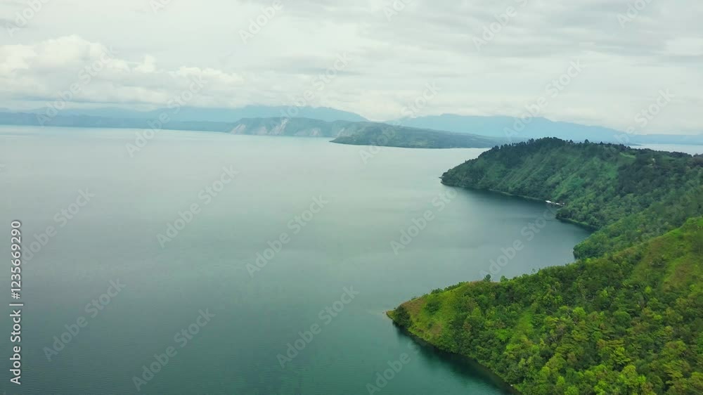 Aerial Ultra HD drone glides over green hills with pine trees and shrubs, capturing the vast, calm Lake Toba at the foot of the slopes in a breathtaking, serene view Aerial Ultra HD drone glides over green hills with pine trees and shrubs, capturing the vast, calm Lake Toba at the foot of the slopes in a breathtaking, serene view