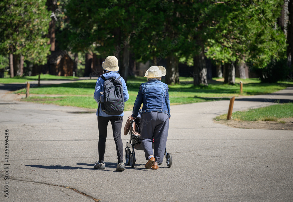 Senior woman walking with a mobility walker in a park, talking with adult daughter. Lake Tahoe. California.