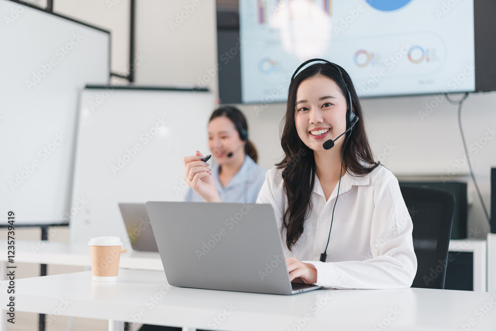 smiling customer service representative wearing headset works on laptop in modern office smiling customer service representative wearing headset works on laptop in modern office