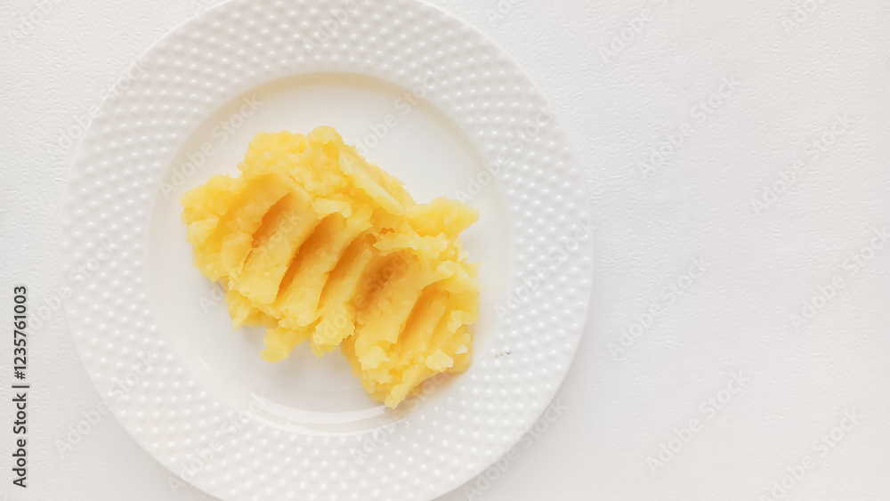 There is mashed potatoes in a white saucer on the table, top view, a place for text on the right side. Second course or side dish. Background for the menu in the restaurant, dining room. There is mashed potatoes in a white saucer on the table, top view, a place for text on the right side. Second course or side dish. Background for the menu in the restaurant, dining room.