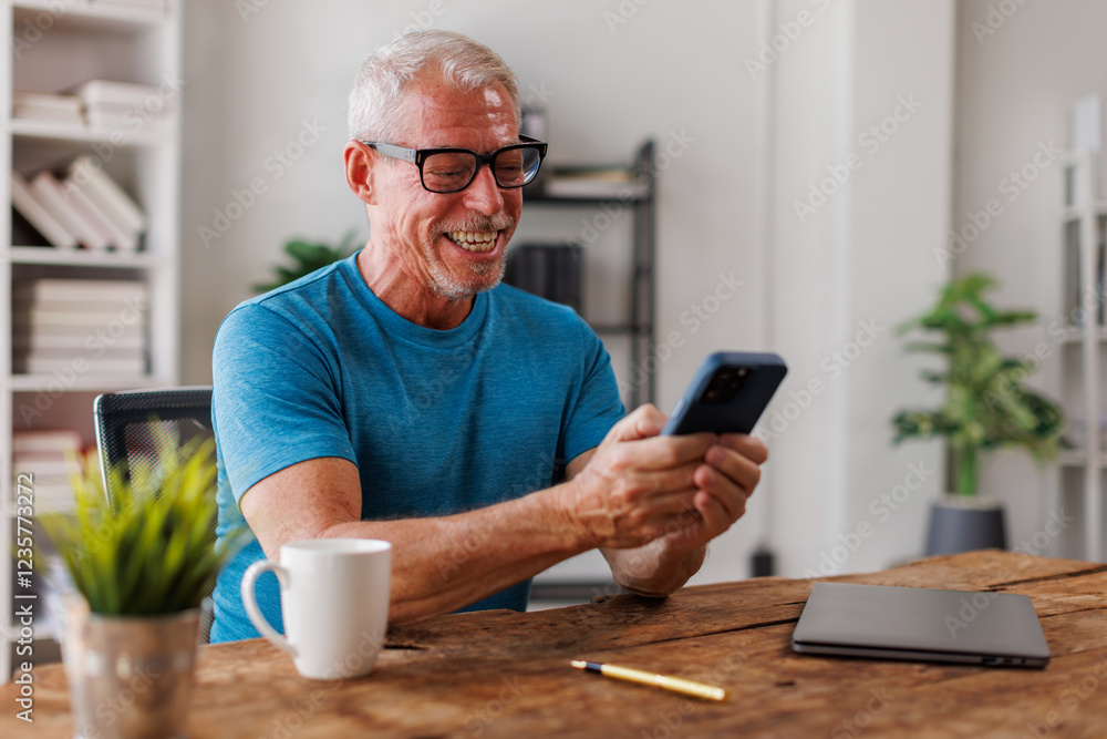 50s man, Senior, man checking news on phone and laptop at home. Confident happy smiling. 50s man, Senior, man checking news on phone and laptop at home. Confident happy smiling.