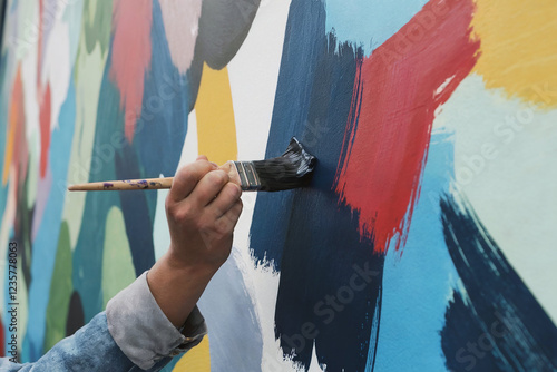 Artist applying vibrant paint to a mural