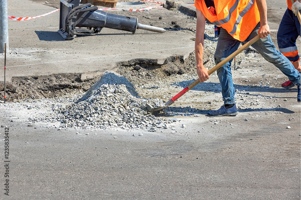 Construction workers engaged in road repair activity on a sunny day. Copy space.