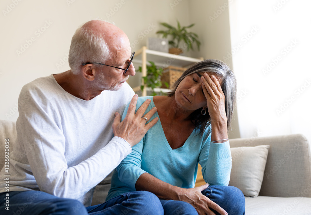 Mature man consoling sad wife sitting on the sofa at home living room. Mature man consoling sad wife sitting on the sofa at home living room.