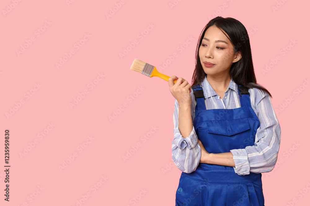 Female Asian thoughtful painter with brush on pink background Female Asian thoughtful painter with brush on pink background