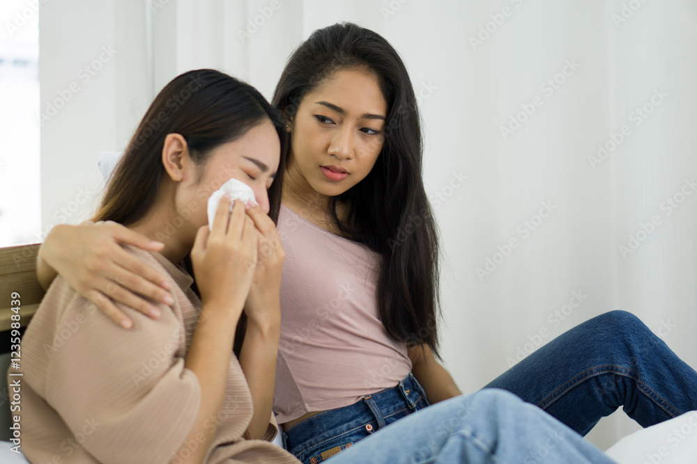 Young asian woman comfort another who is visibly crying, sitting close together in a softly lit room. They share a moment of connection and understanding. Young asian woman comfort another who is visibly crying, sitting close together in a softly lit room. They share a moment of connection and understanding.