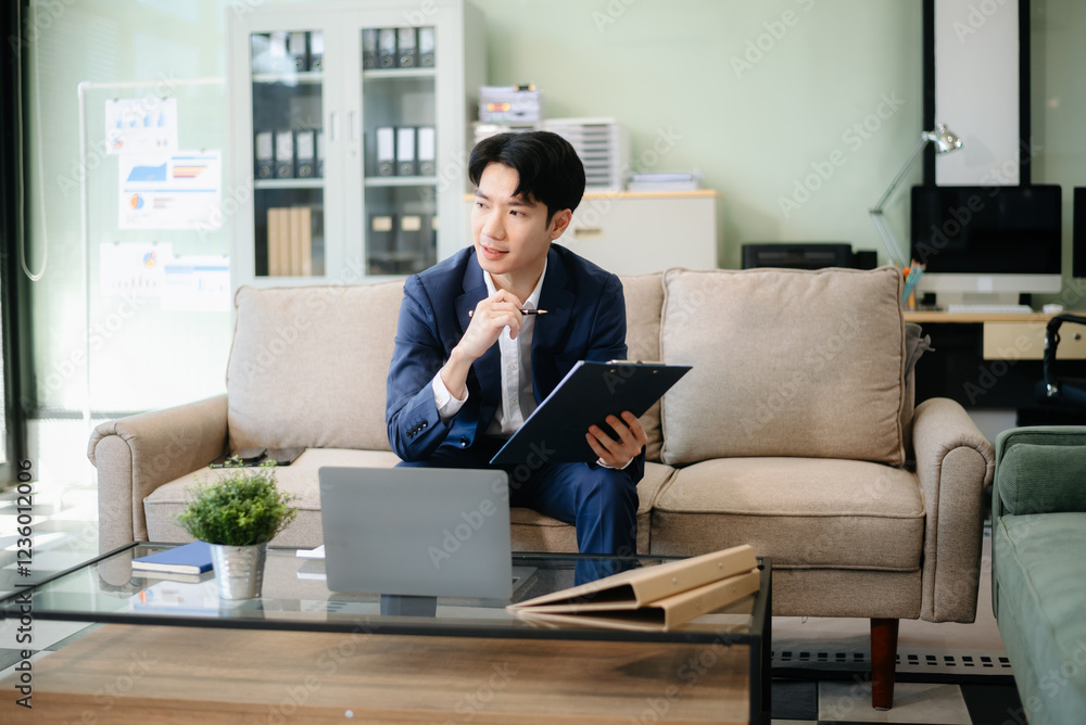 Confident young businessman working on a laptop, analyzing documents in a stylish modern office. Confident young businessman working on a laptop, analyzing documents in a stylish modern office.