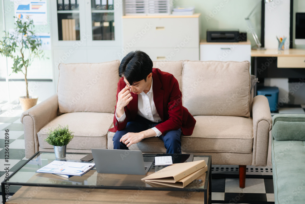 Confident young businessman working on a laptop, analyzing documents in a stylish modern office. Confident young businessman working on a laptop, analyzing documents in a stylish modern office.