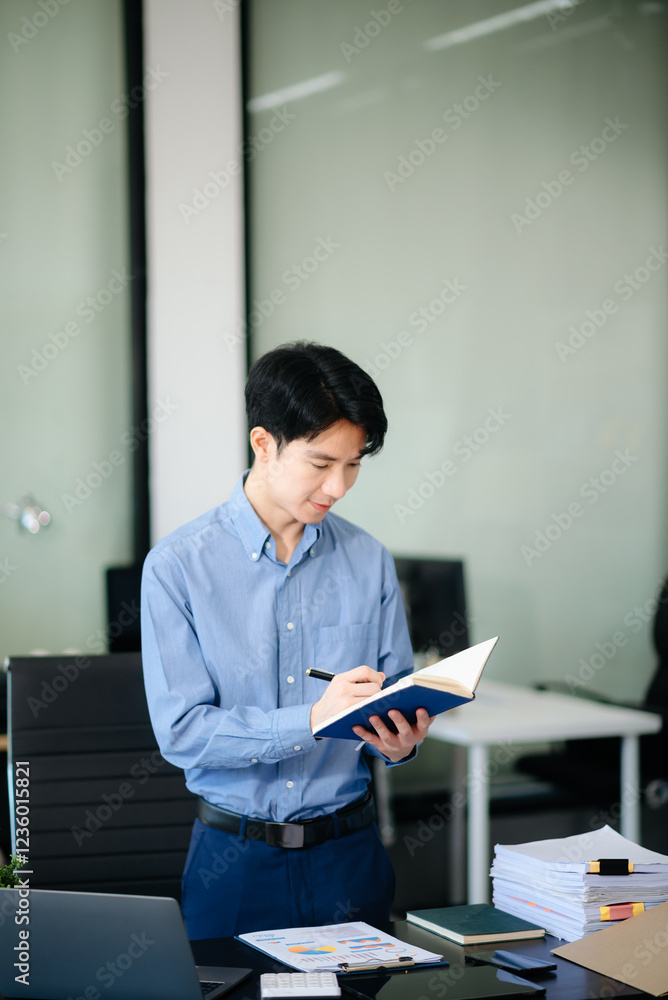Confident Asian businessman typing laptop computer and digital tablet at office Confident Asian businessman typing laptop computer and digital tablet at office