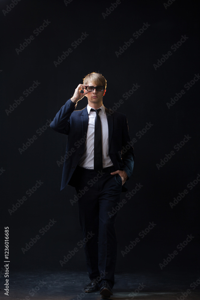 confident man strides forward in a dark suit, exuding authority and professionalism. The low-key, dark background highlights the formal attire in a corporate setting confident man strides forward in a dark suit, exuding authority and professionalism. The low-key, dark background highlights the formal attire in a corporate setting