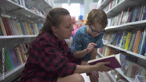Little boy in glasses and his mother are choosing book