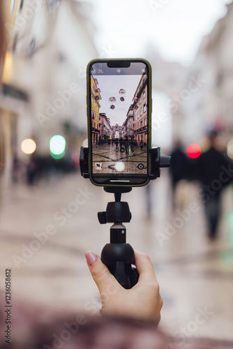 Close up of woman's hand with phone recording video share via app her travel vacation in the Lisbon. Woman influencer shooting social media stories on the street leading to Commerce Square.