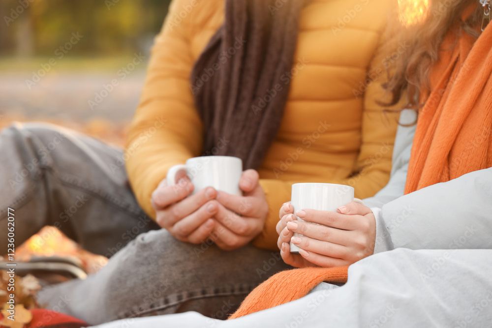 Beautiful loving young couple with cups of tea sitting in autumn park, closeup Beautiful loving young couple with cups of tea sitting in autumn park, closeup