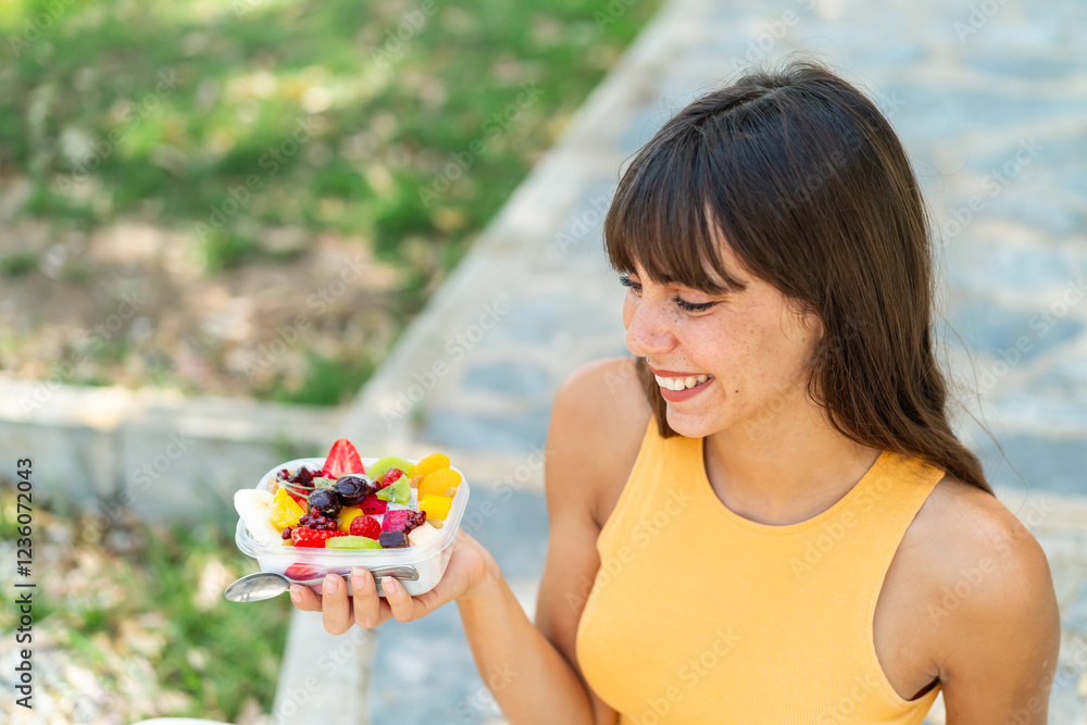 Young woman holding a bowl of fruit at outdoors with happy expression Young woman holding a bowl of fruit at outdoors with happy expression
