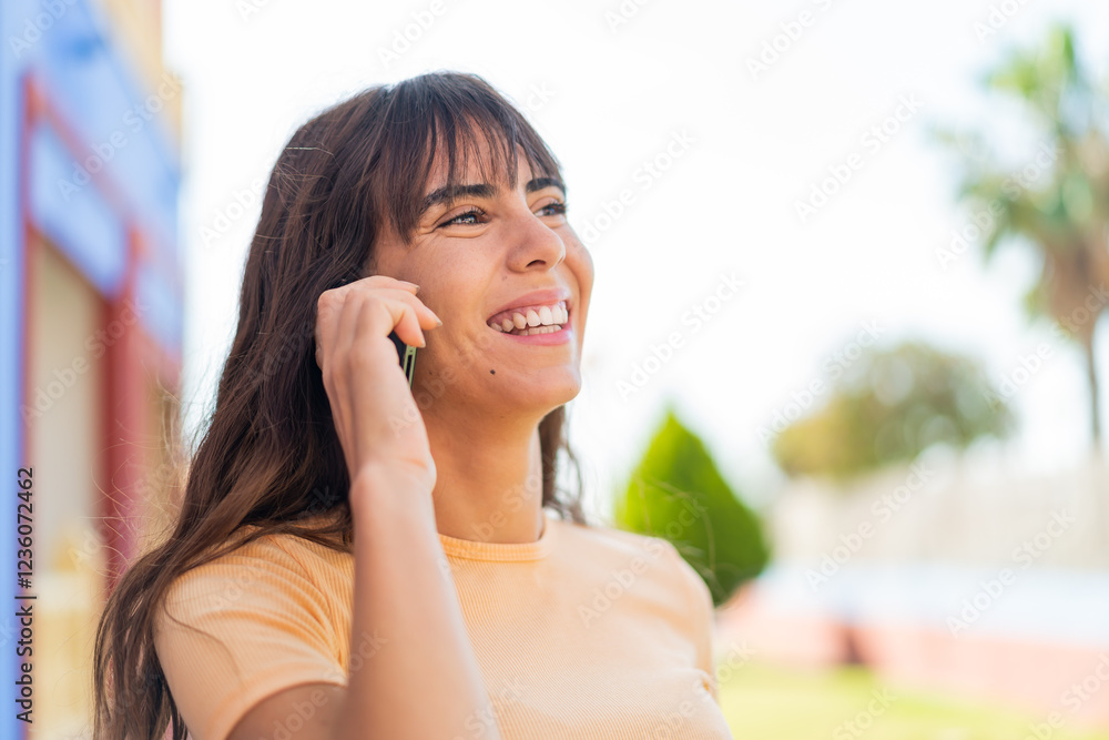 Young woman at outdoors keeping a conversation with the mobile phone Young woman at outdoors keeping a conversation with the mobile phone