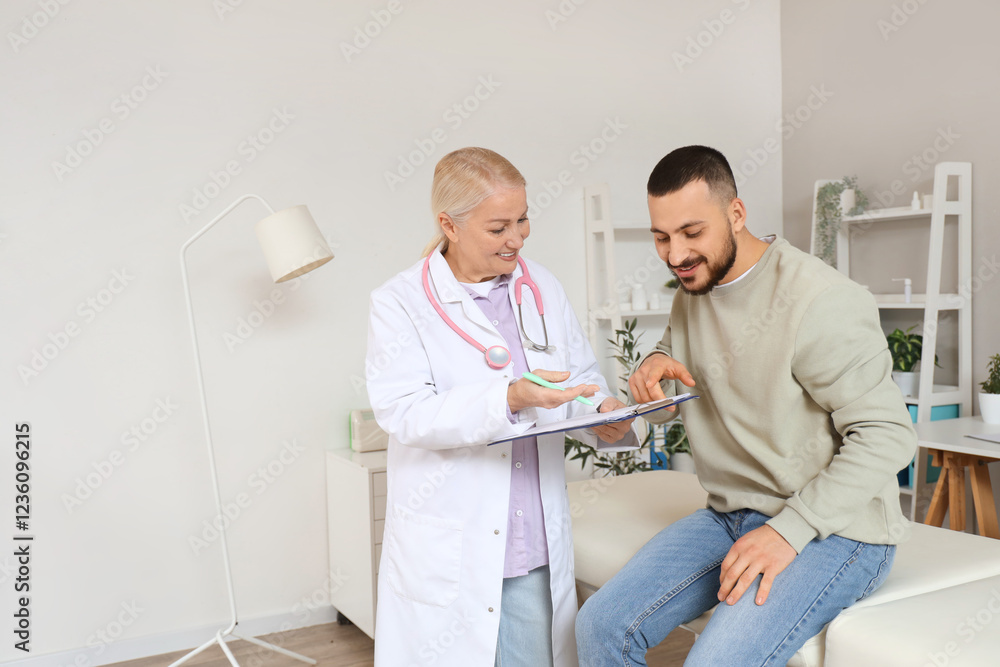 Fototapeta premium Female doctor working with young man in clinic