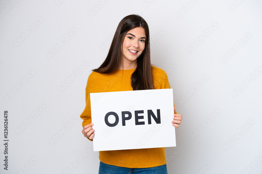 Young Brazilian woman isolated on white background holding a placard with text OPEN with happy expression Young Brazilian woman isolated on white background holding a placard with text OPEN with happy expression