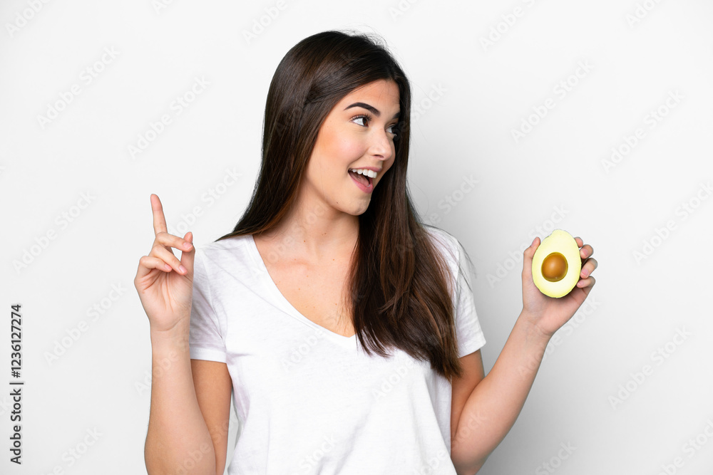 Young Brazilian woman holding an avocado isolated on white background intending to realizes the solution while lifting a finger up Young Brazilian woman holding an avocado isolated on white background intending to realizes the solution while lifting a finger up