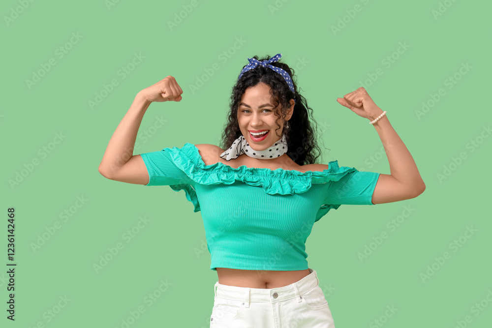 © Pixel-Shot - Young African-American pin-up woman showing muscles on green background. Women's History Month