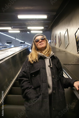 Young girl with glasses riding on moving staircase
