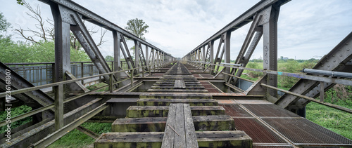 Diminishing view of an abandoned rusty railroad bridge made of steel framework, lost place photo