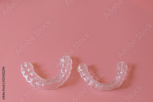 Transparent aligners, invisalign bracer smile isolated on pastel light pink background.