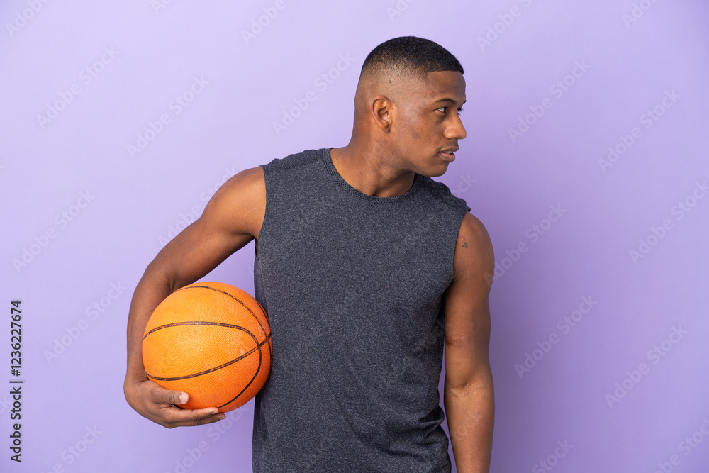 Young basketball latin player man isolated on purple background looking to the side Young basketball latin player man isolated on purple background looking to the side