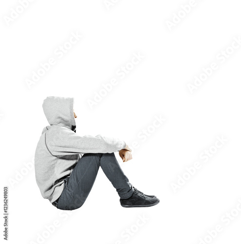 Fotografie Side view of a person sitting with legs bent, wearing a gray hoodie and dark pants, isolated on a white background