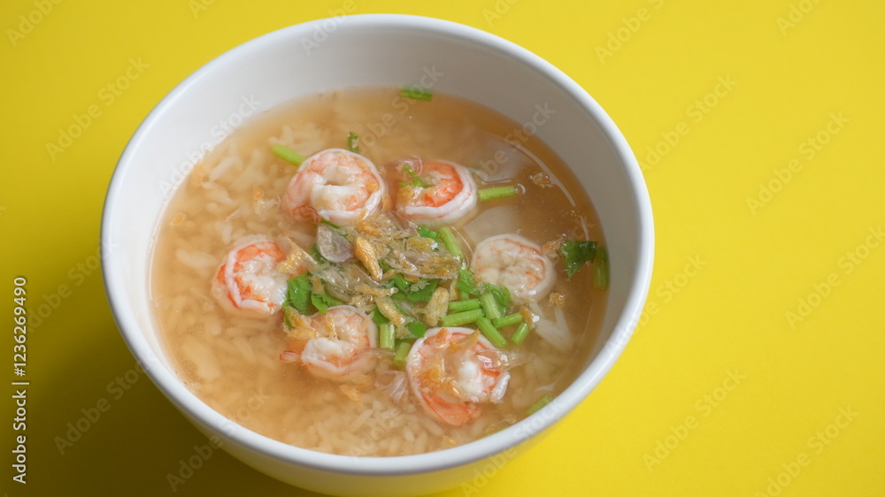 rice soup with shrimp in white bowl on yellow background rice soup with shrimp in white bowl on yellow background