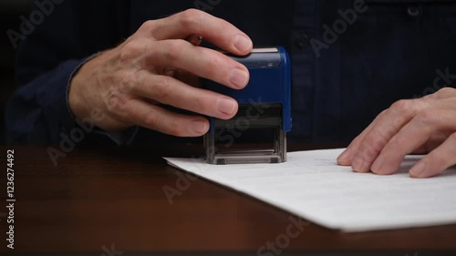 unknown businessman signs and stamps an official document. close-up of a male hands signing a contract, an agreement. concept of document management. front view.