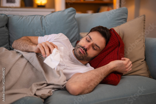 Sick man lie on bed at home. Looking at a handkerchief