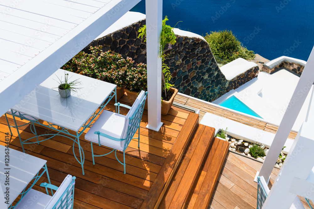 White architecture in Santorini island, Greece. Two chairs with table on the terrace with sea view.