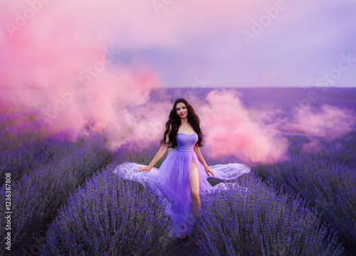Beautiful woman with long hair in a purple dress in a field of blooming lavender. Fairytale lavender field with pink smoke.