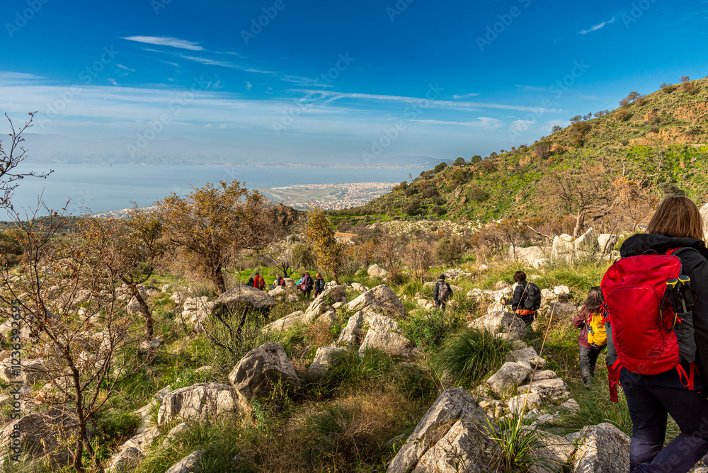 Escursionisti scendono un antico sentiero in pietra e sullo sfondo il lato sud della città di Reggio Calabria Escursionisti scendono un antico sentiero in pietra e sullo sfondo il lato sud della città di Reggio Calabria