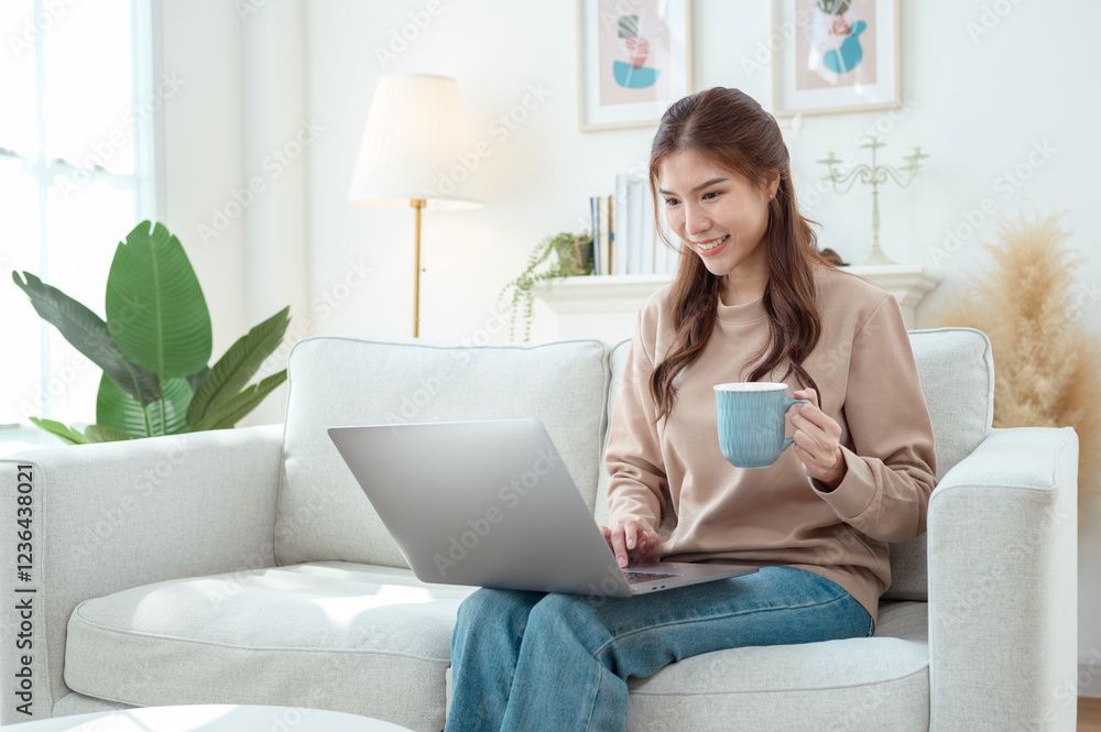 Young Woman Enjoys Working on a Laptop While Sipping Coffee in a Cozy Living Room Setting Young Woman Enjoys Working on a Laptop While Sipping Coffee in a Cozy Living Room Setting