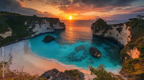 The most beautiful sunset, with an aerial view of the cove, a stunning blue lagoon and beach. The sun sets over sea cliffs, casting warm hues across clear turquoise waters. 