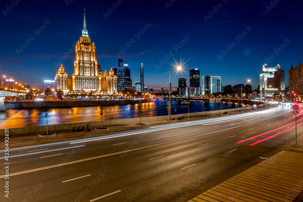Obraz premium Illuminated high-rise stalinist building near river at summer night in Moscow, Russia. Historic name is Hotel Ukraina. Translation of the inscription on the facade: Ukraine