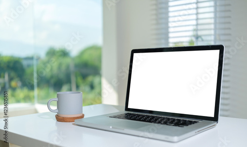 Laptop with a blank white screen and a cup of coffee on white table.