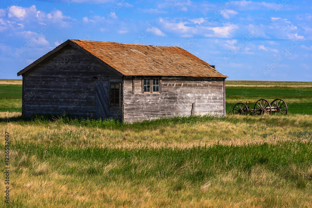 A small, old, wooden house sits in a field of grass A small, old, wooden house sits in a field of grass